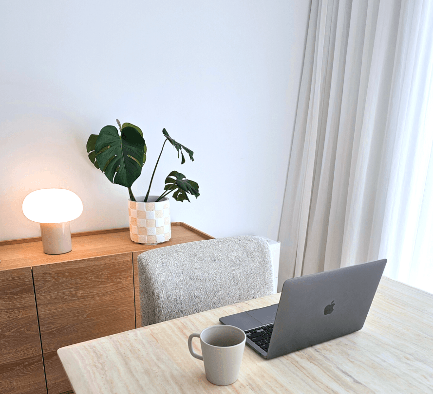 Minimal workspace with laptop, mug, and monstera plant